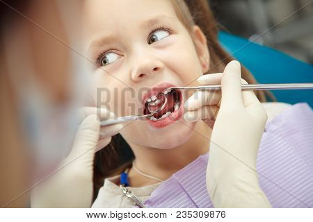 Child Lies In Comfortable Dentis Chair And Goes Through Procedure Without Fear While Female Doctor I