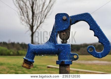 Bright Blue Water Spigot Next To A Field.
