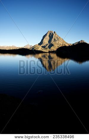 Midi Dossau Peak reflected in Gentau lake. Ossau Valley, Pyrenees National Park, Pyrenees, France.