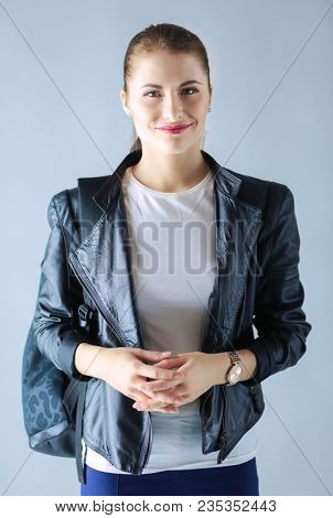 portrait of beautiful young brunette woman in stylish black jacket on gray.