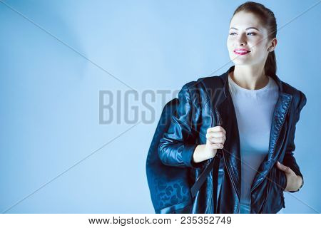 portrait of beautiful young brunette woman in stylish black jacket on gray.