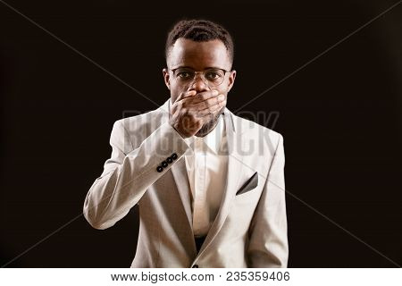 Close Up Portrait Of Surpresed Black Model Closing His Mouth With Hand. Concept Of Shock, Silence. E