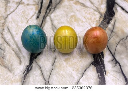 Red, Blue, Yellow Easter Eggs. Three Multicolored Handmade Easter Eggs On A Blue Wooden Background. 