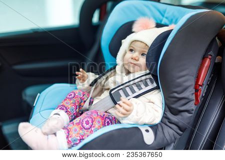 Adorable Baby Girl With Blue Eyes Sitting In Car Seat. Toddler Child In Winter Clothes Going On Fami