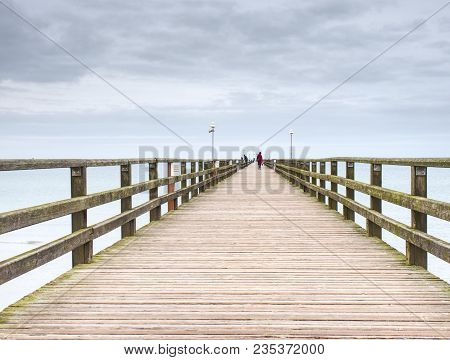 Long Wooden Pier On Baltic Coast During Morning Windless. Cold Weather, Peaceful Silent Day. Empty M