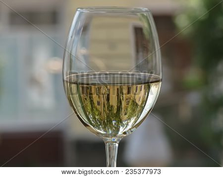 White Wine In A Glass With A Refracted Reflection Of The Building On A Blurred Background