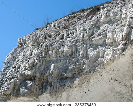 Closeup Chalk Cliff And Sparse Dry Grass On A Clear Blue Sky Background