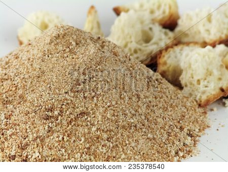 A Pile Of Breadcrumbs On A Blurry Light Background Of Pieces Of White Bread