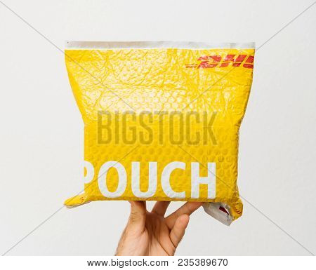 Paris, France - Mar 24, 2018: Male Hand Holding Against White Background A Dhl Express Yellow Parcel