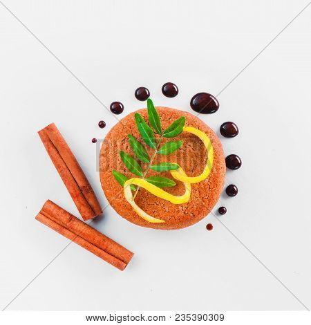Cookie Decorated With Lemon Zest, Chocolate Drops, Cinnamon And Green Leaves On A White Background. 