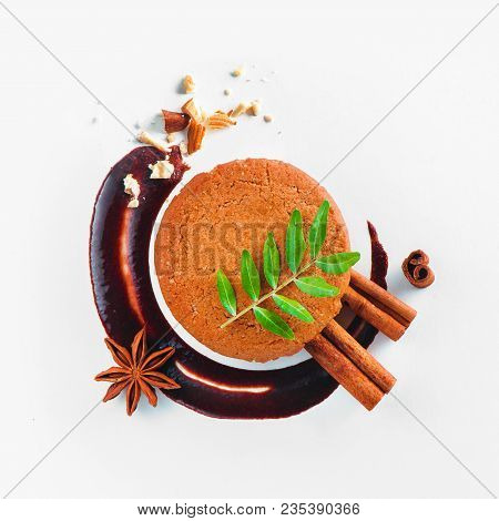 Cookie Decorated With A Chocolate Swoosh, Cinnamon, Anise Star And Green Leaves On A White Backgroun