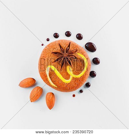 Cookie Decorated With Lemon Zest, Chocolate Drops, Anise Star, Almond And Green Leaves On A White Ba