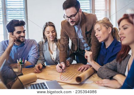 Business, Technology And Office Concept - Business Team On Meeting In Modernoffice Interior And Work