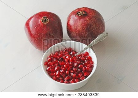 Grains Of Red Ripe Pomegranate Lie In A White Bowl With A Spoon. Big Ripe Red Granets Or Garnets. Fr