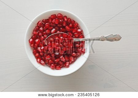 Grains Of Red Ripe Pomegranate Lie In A White Bowl With A Spoon. Big Ripe Red Granets Or Garnets. Fr