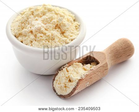 Gram Flour In Bowl And Wooden Scoop Over White Background