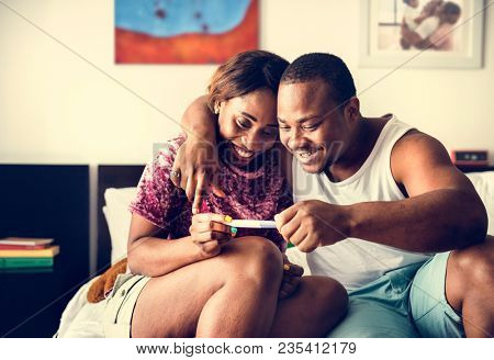 Black couple looking at pregnancy test