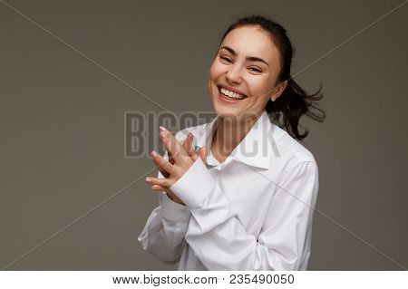 Beautiful Girl In A White Shirt Shows Emotions - Smile, Fun. On A Light Background.