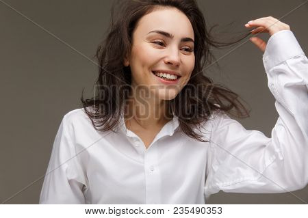 Beautiful Girl In A White Shirt Shows Emotions - Smile, Fun. On A Light Background.