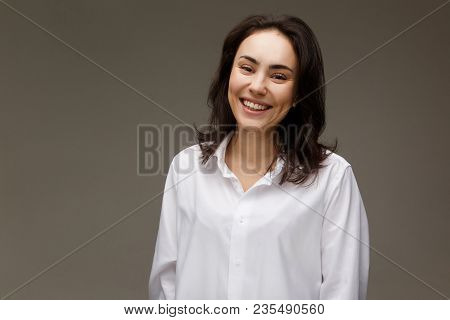 Beautiful Girl In A White Shirt Shows Emotions - Smile, Fun. On A Light Background.