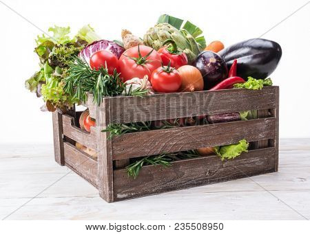 Fresh multi-colored vegetables in wooden crate. Organic food. White background.