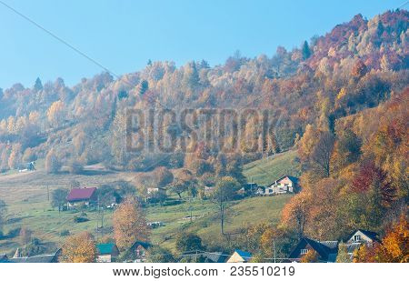 Autumn Carpathian Mountains Landscape With Multicolored Trees And Small Hamlet On Slope, And Misty C