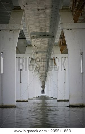 Long Corridor Of Bridge Colomns Over The River