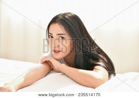 Lifestyle Concept. Cute Asian Girl In Night Dress. Beautiful Asian Woman Is Relaxing In A White Bedr