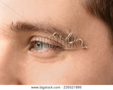 Young man with pierced eyebrow on light background, closeup