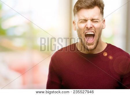 Handsome young man stressful, terrified in panic, shouting exasperated and frustrated. Unpleasant gesture. Annoying work drives me crazy