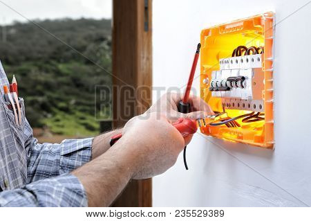 Electrician Technician Working On A Residential Electric Panel, Inserting The Wire With The Clamp