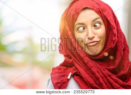 Young arab woman wearing hijab making funny face fooling