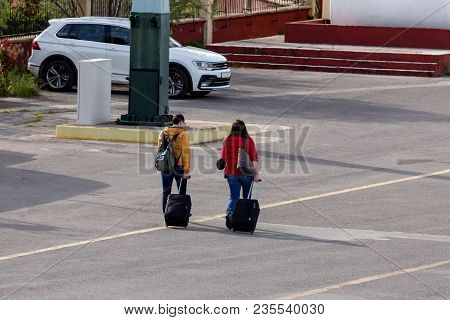 Young Couple With Luggage Go To The Port On The Road (rear View)