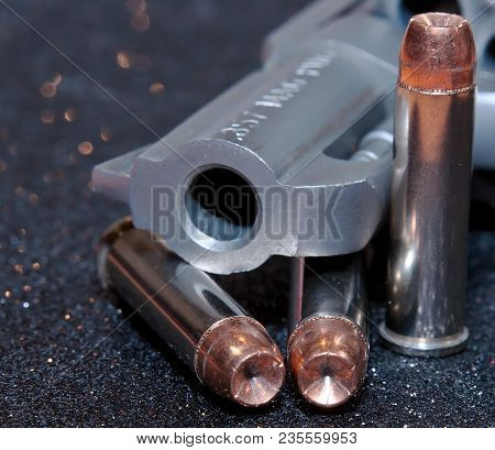 A Loaded, Stainless 357 Snub Nosed Revolver With Three Bullets Next To It, 357 Magnum Is Stamped Int