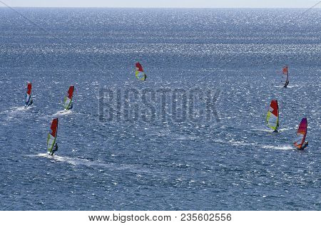 Seven Windsurfers Are Riding On The Surface Of The Dazzling Beautiful  Mediterranean Sea On Cape Pra