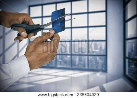 Composite image of businessman cutting credit card with scissors