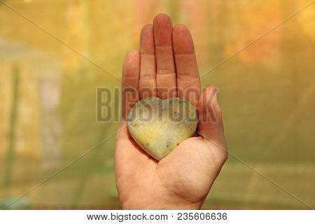 The Hand Holds A Heart Made Of Natural Stone Yellow Jadeite. Heart In Hand. A Stone In The Shape Of 