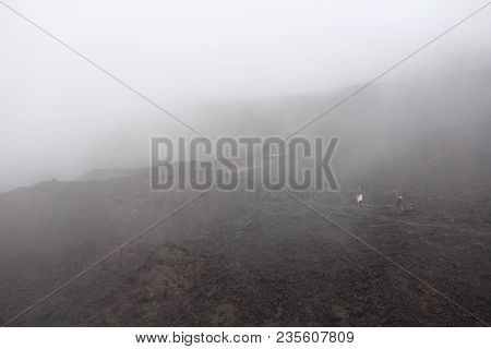 The Etna Volcano. Black Volcanic Earth And Thick Fog On Mount Etna. Place For Text. The Island Of Si