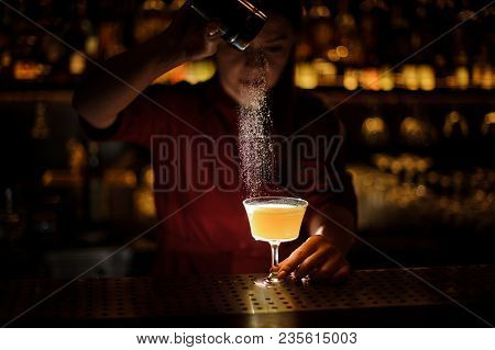 Female Bartender Serving A Fresh Delicious Yellow Cocktail And Pouring A Spice Into It On The Bar Co