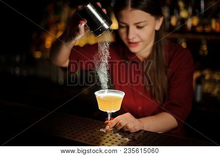 Female Bartender Serving A Fresh Yellow Cocktail And Pouring A Spice Into It On The Bar Counter