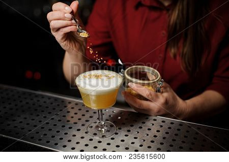 Female Bartender Serving A Fresh Delicious Yellow Cocktail And Adding Spice To It On The Bar Counter