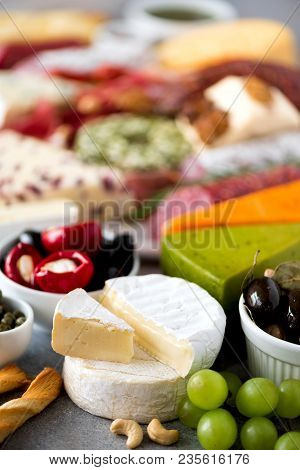Assortment Of Hard, Semi-soft And Soft Cheeses With Olives, Grissini Bread Sticks, Capers, Grape, On