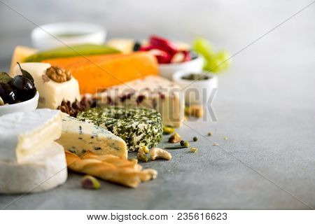Assortment Of Hard, Semi-soft And Soft Cheeses With Olives, Grissini Bread Sticks, Capers, Grape, On