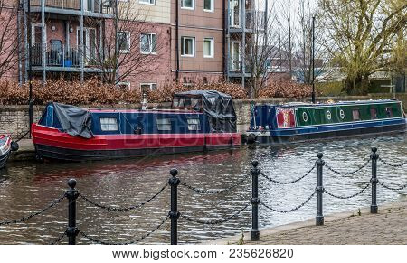 Two Colourful Barges Moored Up On The Canal In Wigan. One Blue And Red And The Other Green