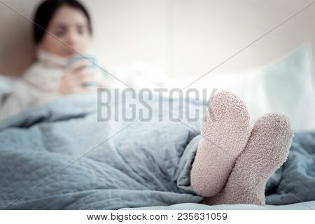 Stay In Bed. Warm Clean Woolen Socks Being On Womans Feet Who Lying On The Bed.