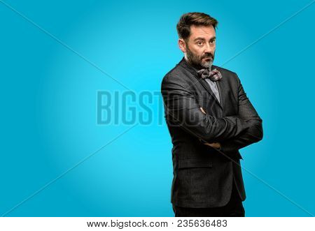 Middle age man, with beard and bow tie with crossed arms confident and happy with a big natural smile laughing
