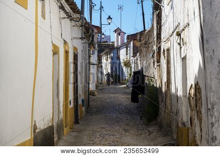 Nisa, Portugal - November 12, 2017: Woman Walking Along A Narrow Cobblestone Street In The Village O