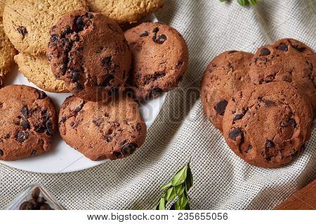 Side View Of A Plate Of Chocolate Chip Cookies On A White Plate Homespun Tablecloth Illuminated With