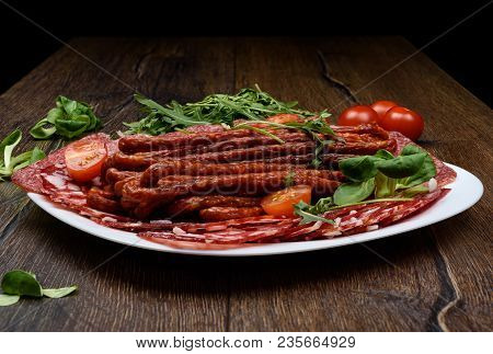 A Plate With Different Types Of Sausage On A Wooden Table. Rustic Style