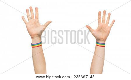 lgbt, same-sex relationships and homosexual concept - close up of male hands wearing gay pride awareness wristbands